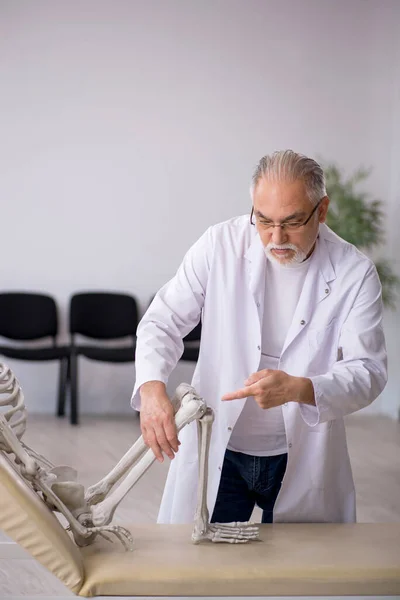 Παλιός άνδρας γιατρός με σκελετό στην κλινική — Φωτογραφία Αρχείου