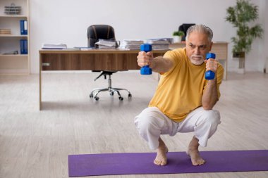 Ofiste spor egzersizleri yapan eski bir işadamı.