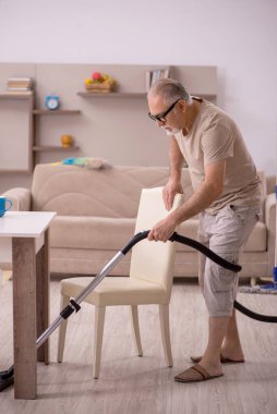 Yaşlı adam evde ev işi yapıyor.