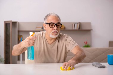 Yaşlı adam evde ev işi yapıyor.