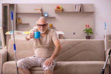 Yaşlı adam evde ev işi yapıyor.