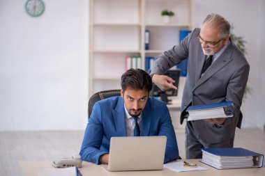 Yaşlı erkek patron ve ofiste çalışan genç erkek çalışan.