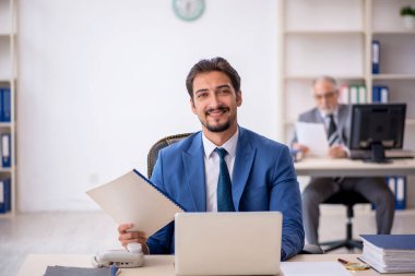 Yaşlı erkek patron ve ofiste çalışan genç erkek çalışan.