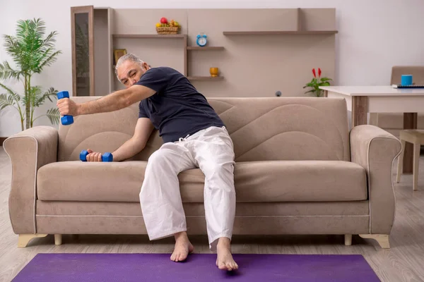 Velho fazendo exercícios esportivos em casa — Fotografia de Stock