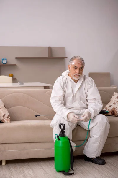 Velho empreiteiro masculino fazendo controle de pragas em casa — Fotografia de Stock