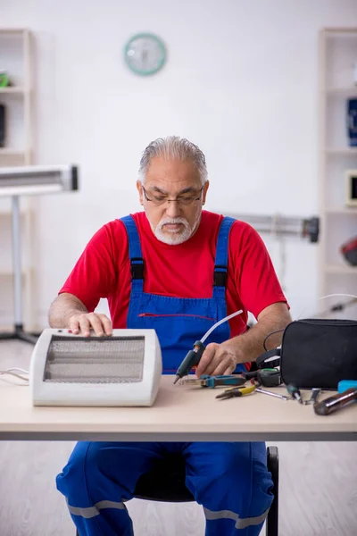 Reparador velho reparando aquecedor na oficina — Fotografia de Stock