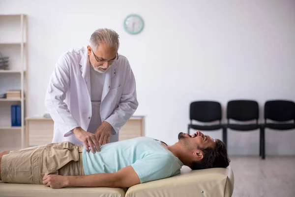 Joven paciente masculino visitando viejo médico masculino — Foto de Stock