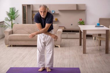 Yaşlı adam evde spor yapıyor.