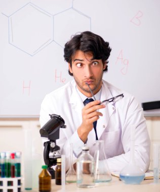 Beyaz panonun önündeki komik genç kimyager.