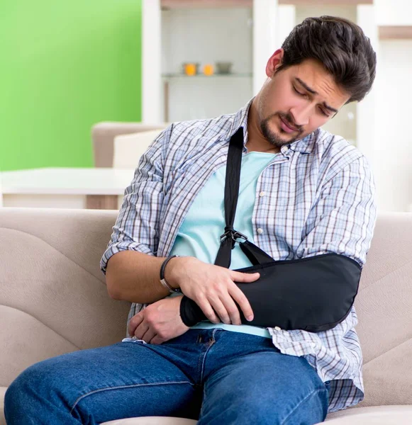 Joven estudiante con lesión en la mano sentado en el sofá —  Fotos de Stock