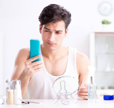 Genç yakışıklı adam aynaya bakıyor.