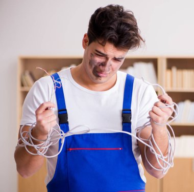 Kablolara dolanmış komik genç elektrikçi.