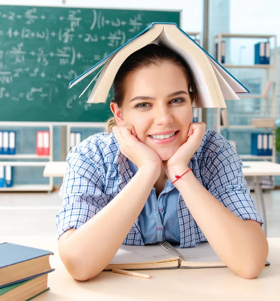 Studentka s mnoha knihami sedící ve třídě — Stock fotografie