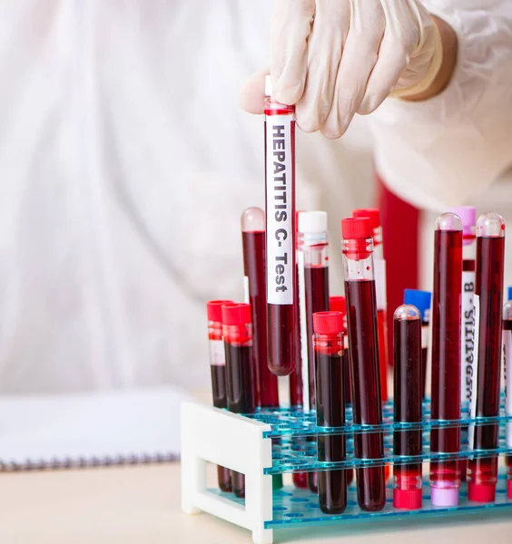 El joven asistente de laboratorio guapo analizando muestras de sangre en el hospicio —  Fotos de Stock