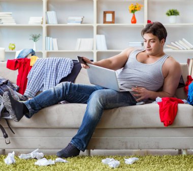 Genç adam dağınık bir odada çalışıyor.