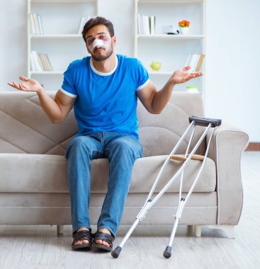 Koltuk değnekli yaralı bir adam evde iyileşiyor.