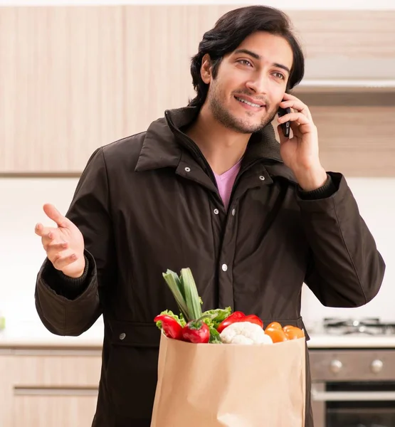 The young handsome man with vegetables in the kitchen — Stock Photo, Image