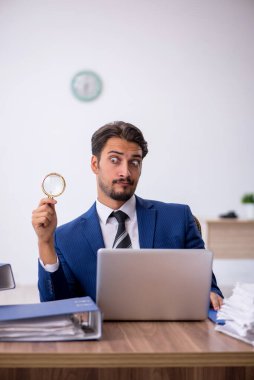 Genç bir erkek çalışan ve ofiste çok fazla iş var.