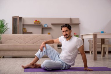 Genç adam evde spor yapıyor.