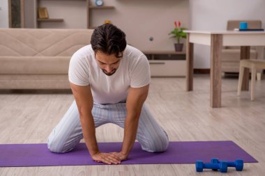 Genç adam evde spor yapıyor.