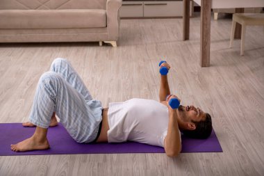 Genç adam evde spor yapıyor.