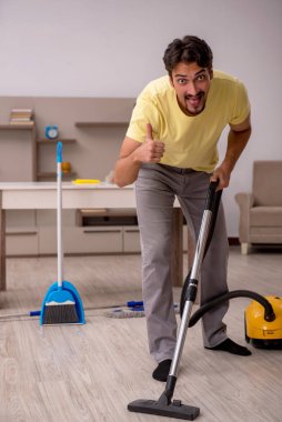 Genç adam evde ev işi yapıyor.