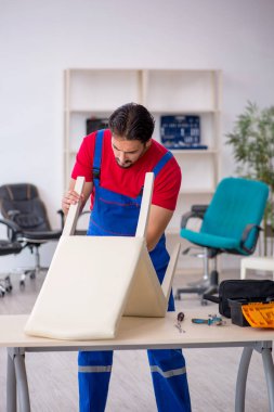 Genç erkek marangoz atölyede çalışıyor.