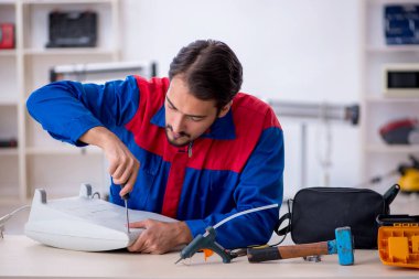 Genç erkek tamirci ısıtıcıyı tamir ediyor.