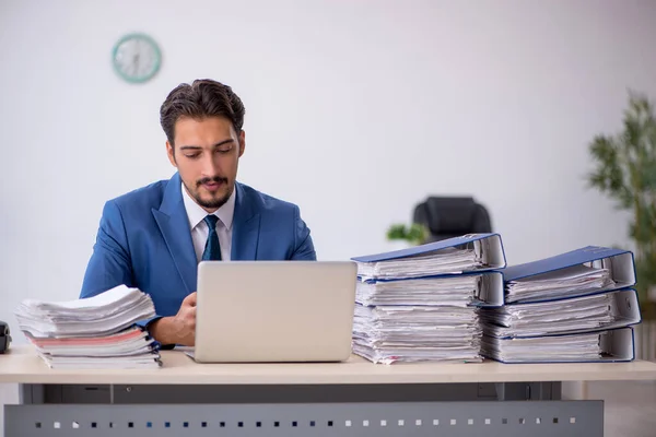 Joven empleado masculino y demasiado trabajo en la oficina — Foto de Stock