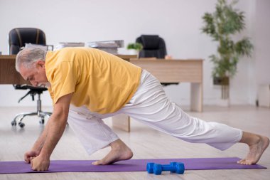 Ofiste spor egzersizleri yapan eski bir işadamı.