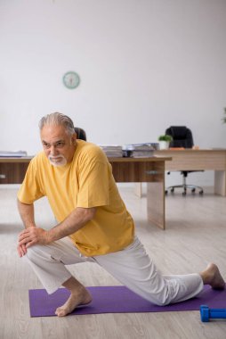 Ofiste spor egzersizleri yapan eski bir işadamı.