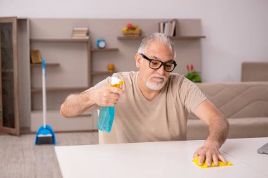 Yaşlı adam evde ev işi yapıyor.