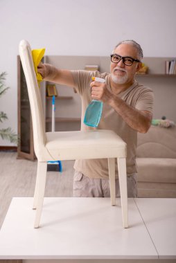 Yaşlı adam evde ev işi yapıyor.