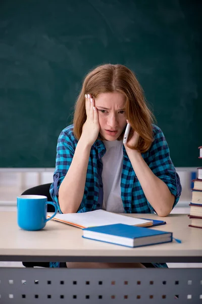 Ung kvinnlig student förbereder sig för tentor i klassrummet — Stockfoto