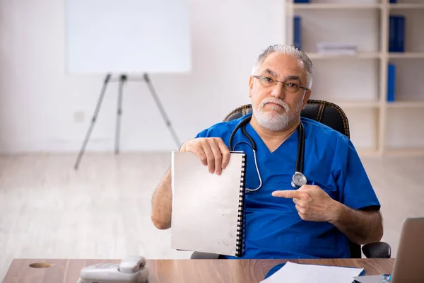 Gammal manlig läkare som arbetar på kliniken — Stockfoto