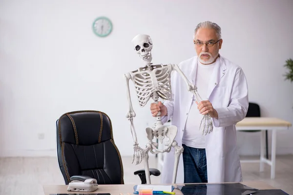 Klinikte iskeleti olan yaşlı bir doktor. — Stok fotoğraf