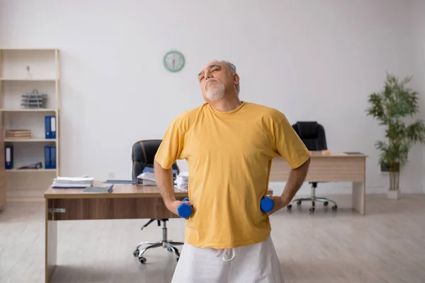 Starý podnikatel zaměstnanec dělá sportovní cvičení v kanceláři — Stock fotografie
