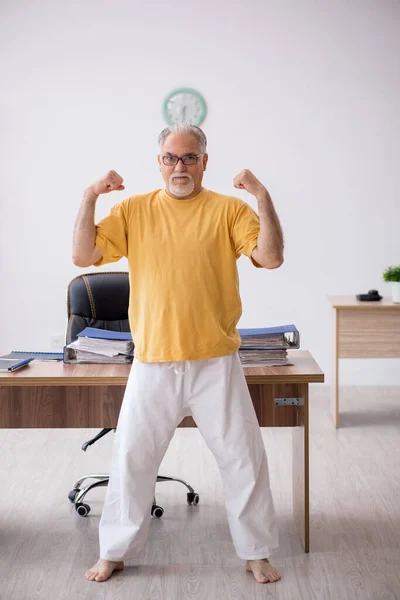 Velho empresário empregado fazendo exercícios esportivos no escritório — Fotografia de Stock