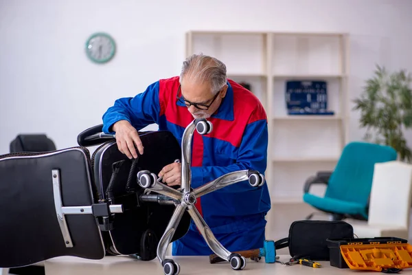 Viejo reparador masculino reparando silla de oficina —  Fotos de Stock