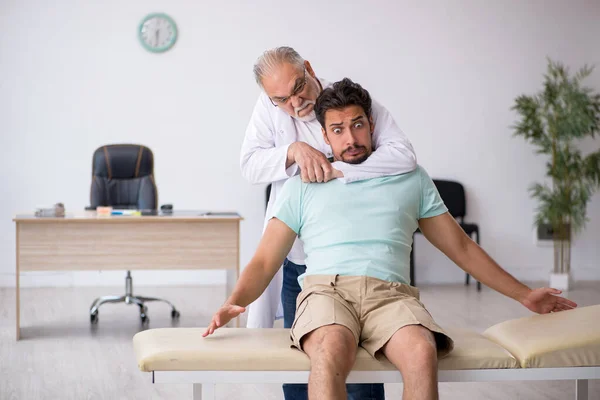 Mladý pacient mužského pohlaví na návštěvě starého lékaře — Stock fotografie