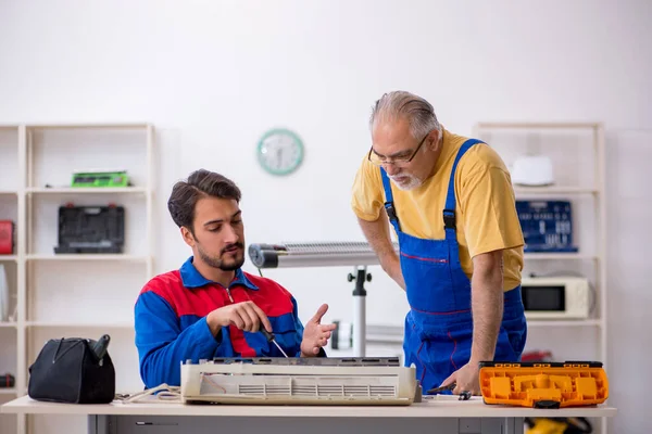 Два ремонтника-мужчины ремонтируют кондиционер — стоковое фото