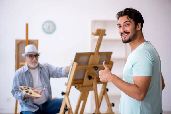 Old painter and young male model at the studio — Stock Photo, Image