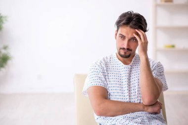 Genç erkek hasta hastanede doktor bekliyor.