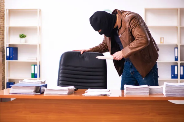 Mladý muž v balaklavě kradoucí informace z kanceláře — Stock fotografie