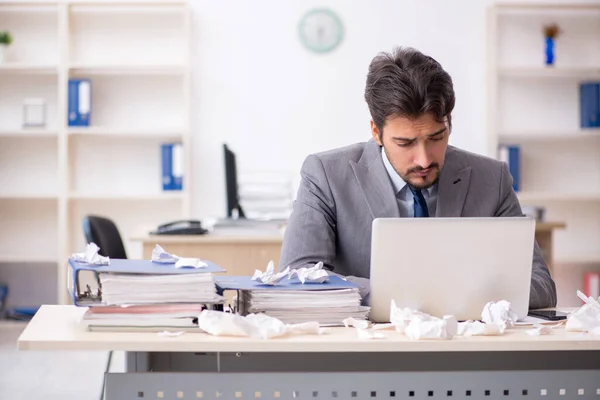 Young male employee and too much work in the office — Stock Photo, Image