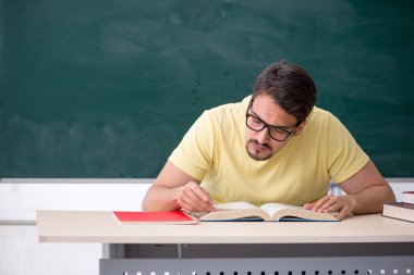 Tahtanın önünde genç bir erkek öğrenci.