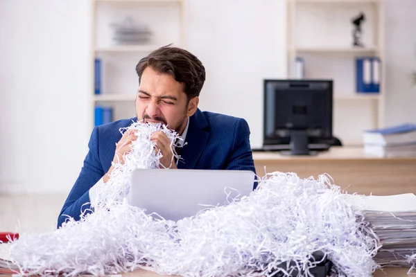 Junge männliche Angestellte und viele geschnittene Papiere im Büro — Stockfoto