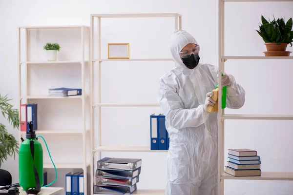 Contratista masculino joven desinfectando oficina durante pandemia — Foto de Stock