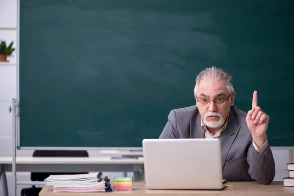 Gammal manlig lärare framför svarta tavlan i telestudy koncept — Stockfoto