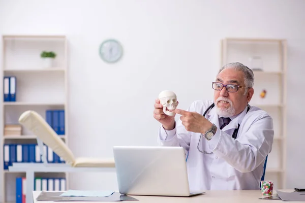 Yaşlı erkek doktor insan kafatasını gösteriyor. — Stok fotoğraf